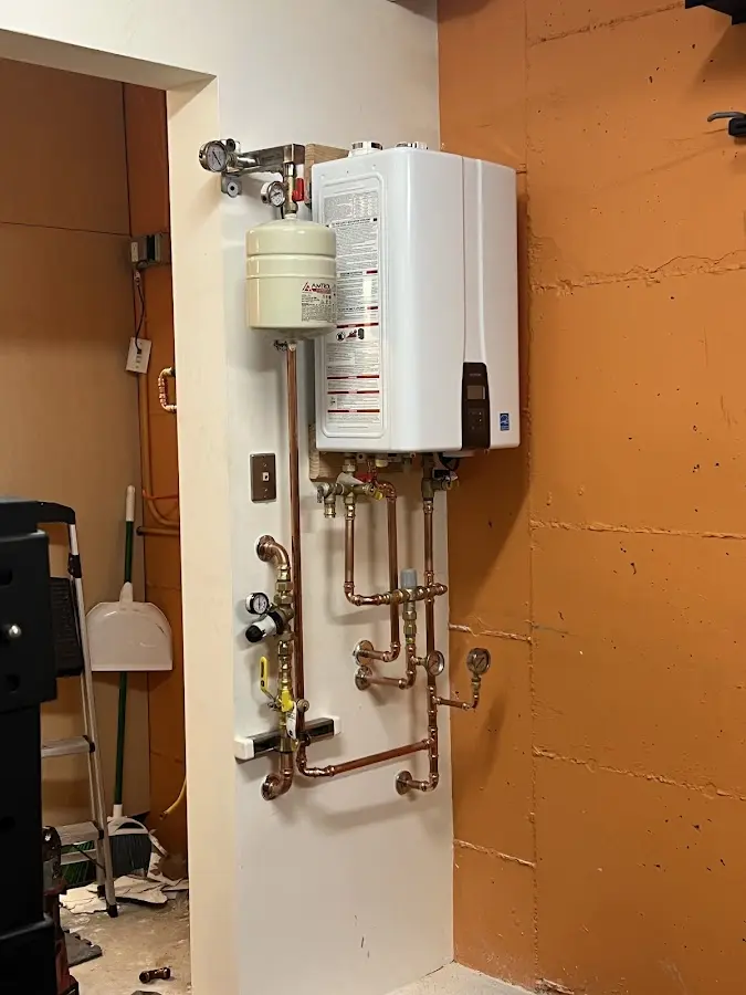Plumbing technician inspecting water heater connections in Atlantic Highlands